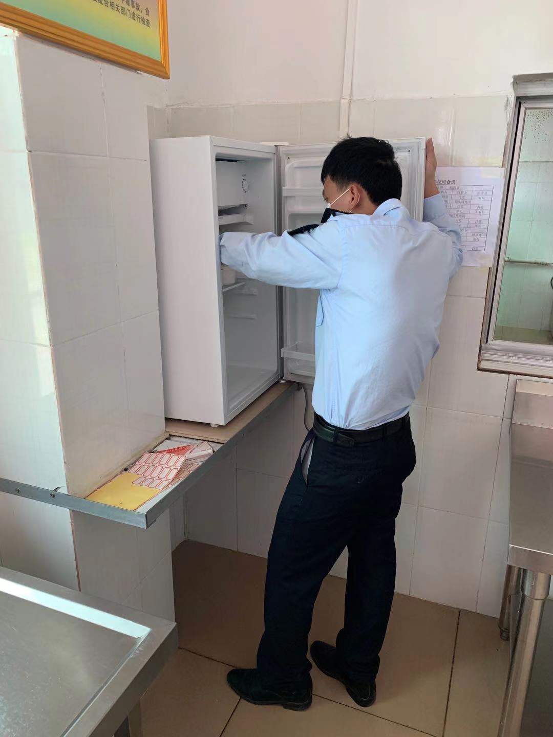 执法人员查看食堂留样冰箱.jpg